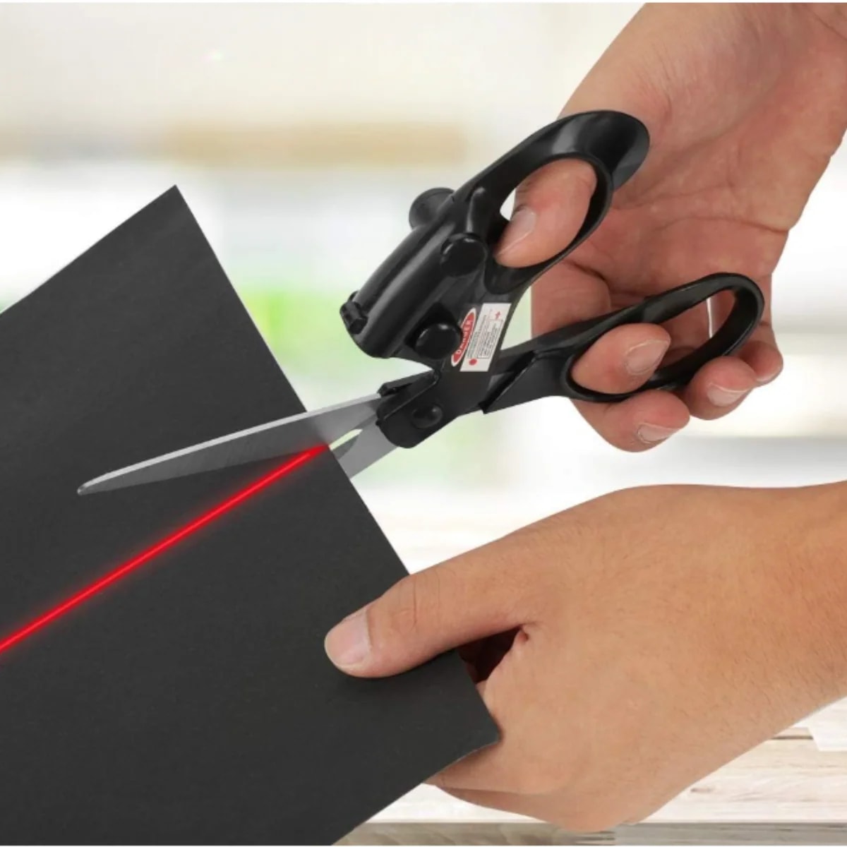 Laser guided scissors cutting black card along a red laser line