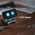 LOOI desktop robot with a smartphone showing animated eyes on a wooden desk
