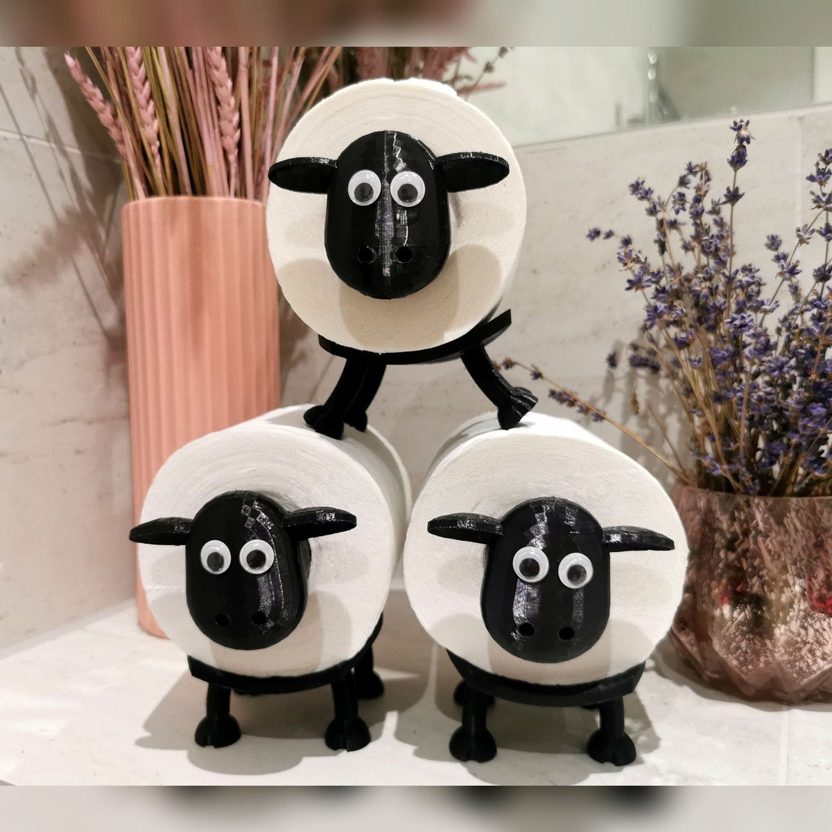 Three stacked sheep toilet roll holders on a bathroom counter