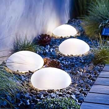 Glowing solar stone lights between plants and pebbles